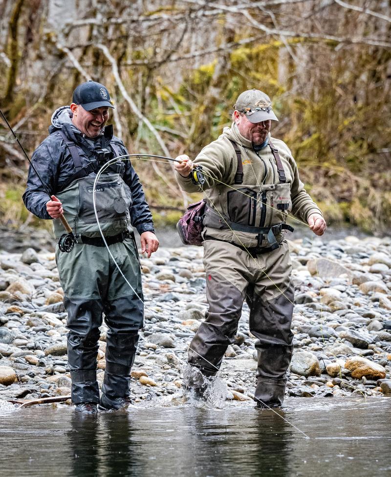 Two anglers fly fishing in a rocky river.