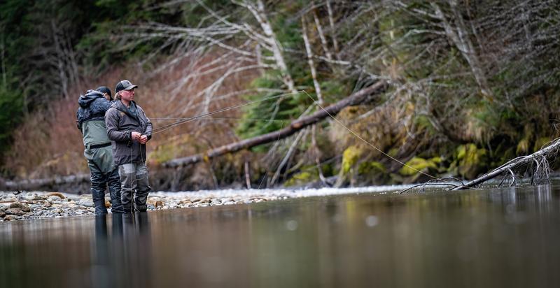 Two fishermen standing in a river with fishing rods