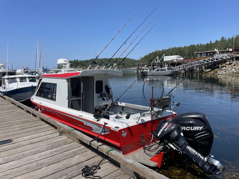 Red and white fishing boat docked at a wooden pier.