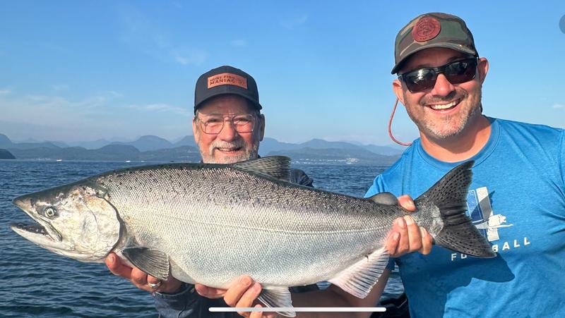 Angler holding a large salmon on a boat.