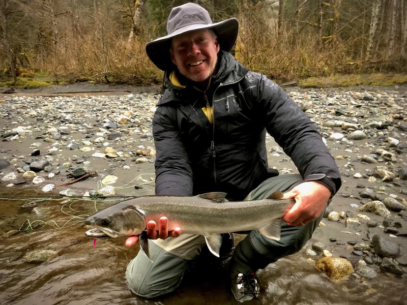 Ben Berukoff, Pilot and guide kneeling on a riverfront with a fish he caught