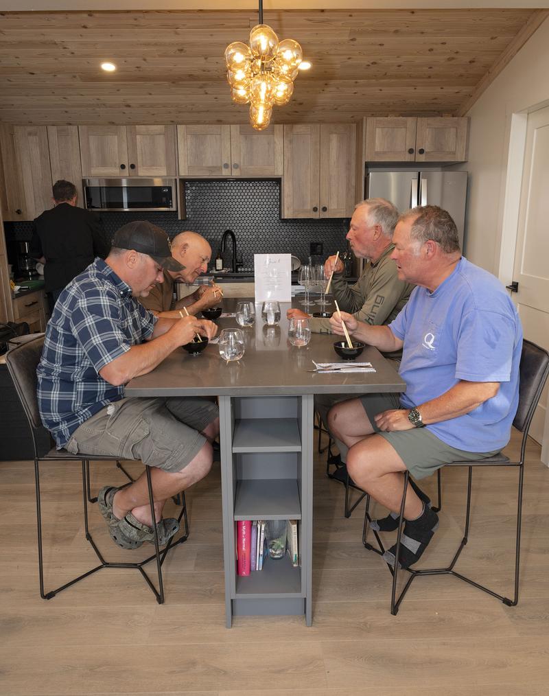 Group of men sitting around a kitchen island, eating and conversing.