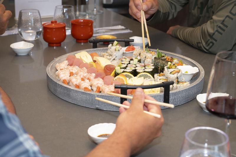 Large platter of sushi that people are eating from with chopsticks