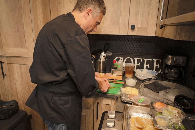 Chef in a black uniform preparing food at a kitchen counter.