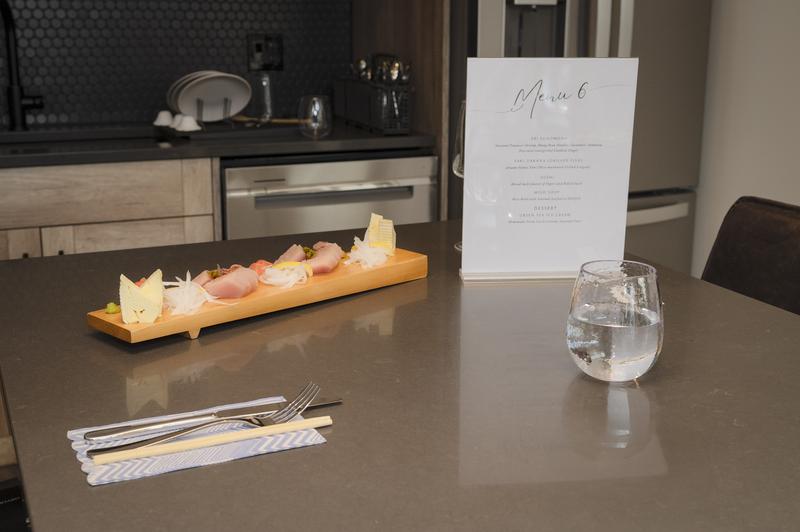 Sushi presented on a wooden stand with a menu beside it