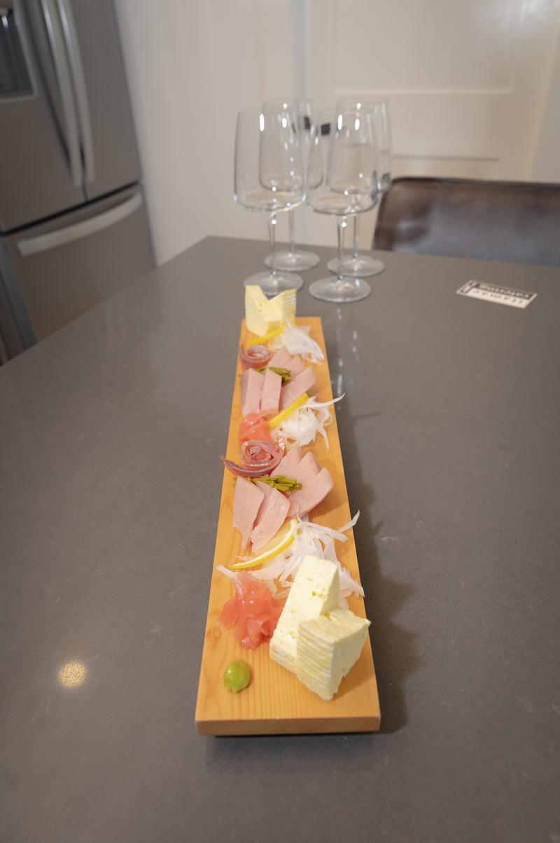 View of the sashimi board on the counter with wine glasses in the background.