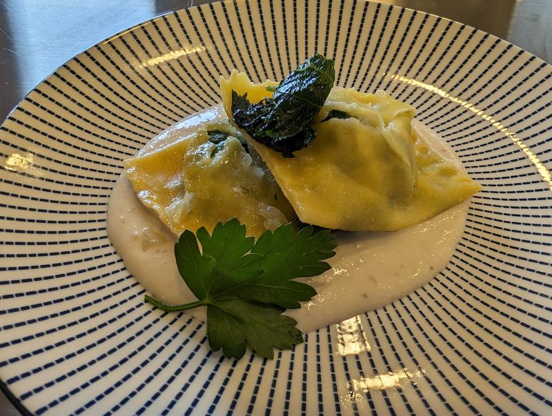 Plate of ravioli in a creamy sauce garnished with fresh parsley.