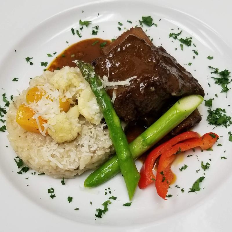 Braised beef short rib served with mashed potatoes, asparagus, and red peppers.