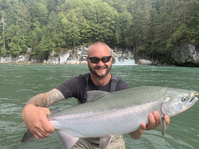 Angler holding a large salmon in a river.